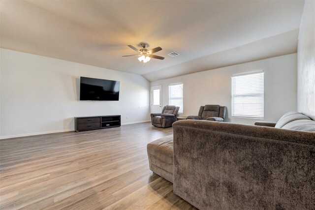 living area featuring visible vents, baseboards, ceiling fan, light wood-style flooring, and vaulted ceiling