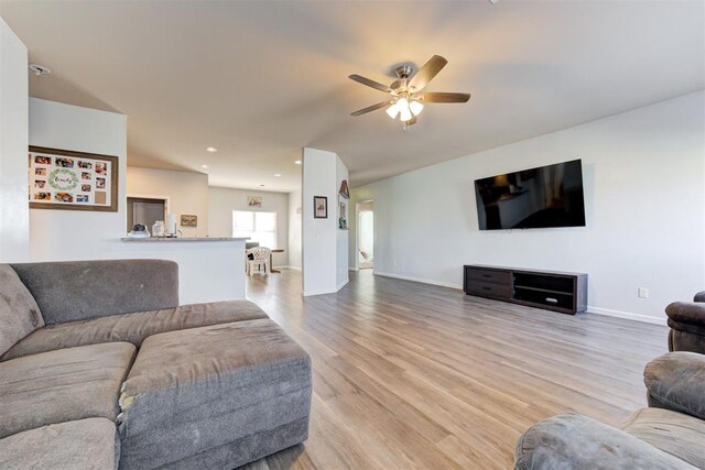 living room with light wood-style flooring, baseboards, a ceiling fan, and recessed lighting