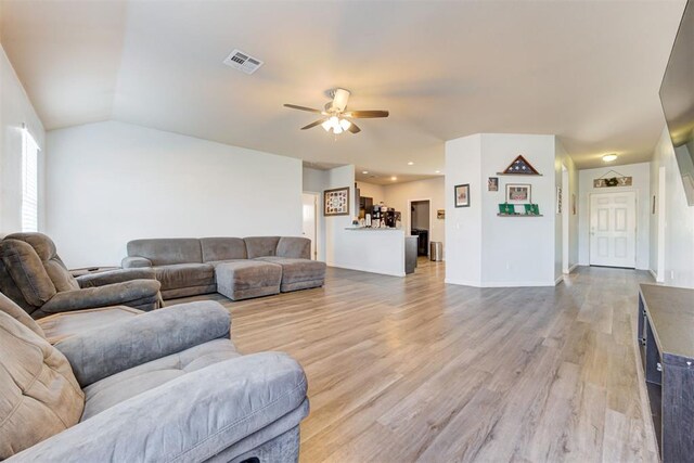 living room with ceiling fan, light wood-style flooring, visible vents, baseboards, and vaulted ceiling