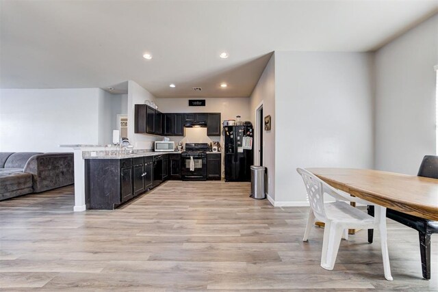 kitchen with recessed lighting, a peninsula, open floor plan, light wood-type flooring, and black appliances