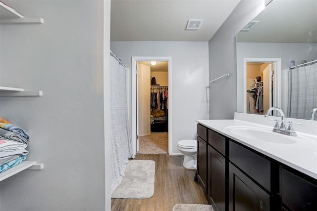 full bathroom with toilet, vanity, wood finished floors, and visible vents