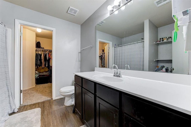 bathroom featuring visible vents, vanity, toilet, and wood finished floors