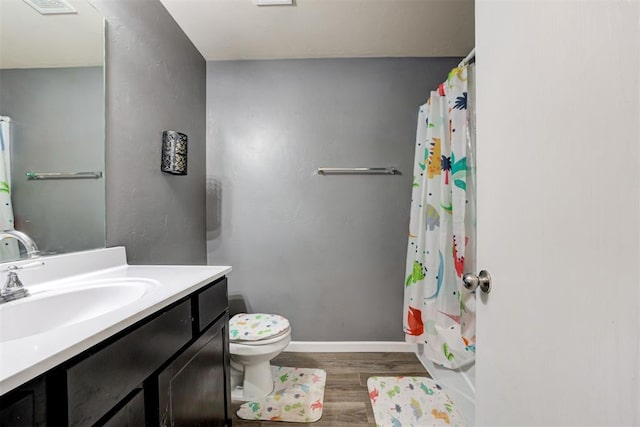 bathroom with vanity, wood finished floors, toilet, and baseboards