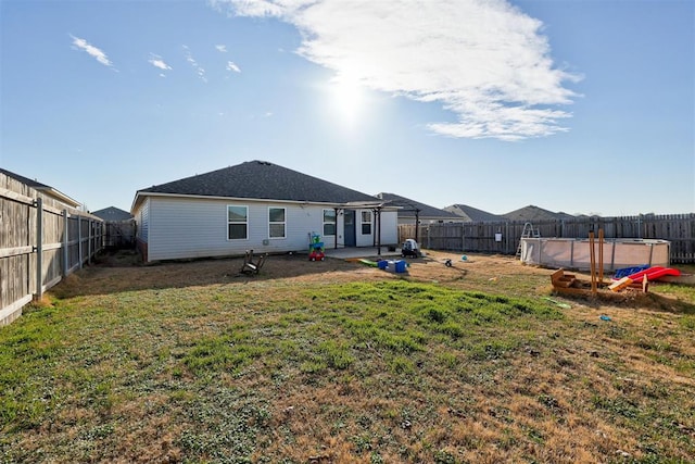 back of house featuring a yard, a patio area, a fenced backyard, and a fenced in pool