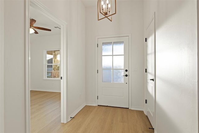 entryway with ceiling fan with notable chandelier and light hardwood / wood-style flooring