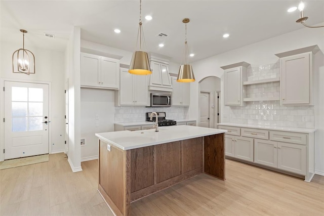 kitchen with a center island with sink, white cabinets, light hardwood / wood-style flooring, and appliances with stainless steel finishes