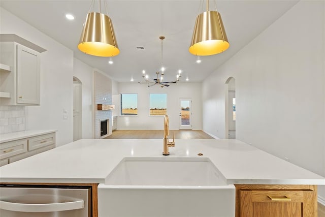 kitchen featuring pendant lighting, decorative backsplash, a fireplace, and sink