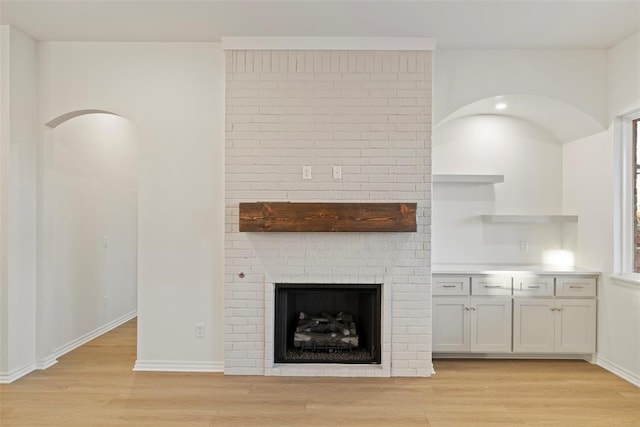 unfurnished living room with light hardwood / wood-style floors and a brick fireplace