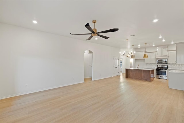 unfurnished living room with ceiling fan with notable chandelier, light hardwood / wood-style floors, and sink