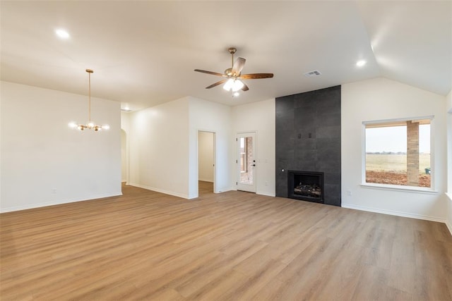 unfurnished living room featuring a tile fireplace, lofted ceiling, light hardwood / wood-style flooring, and ceiling fan with notable chandelier