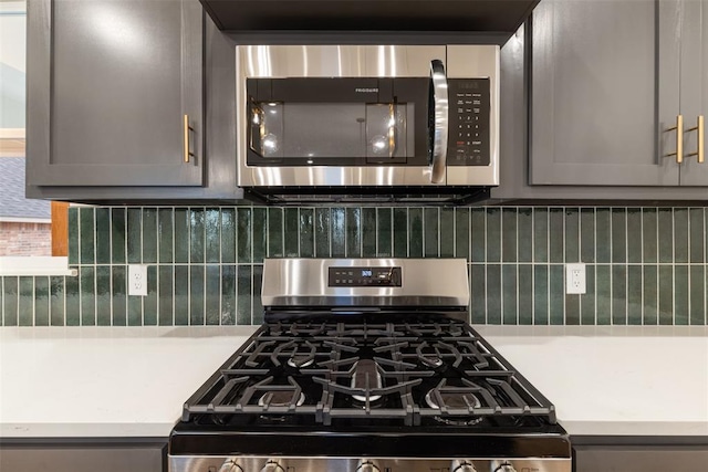 kitchen with backsplash, gray cabinetry, and stainless steel appliances