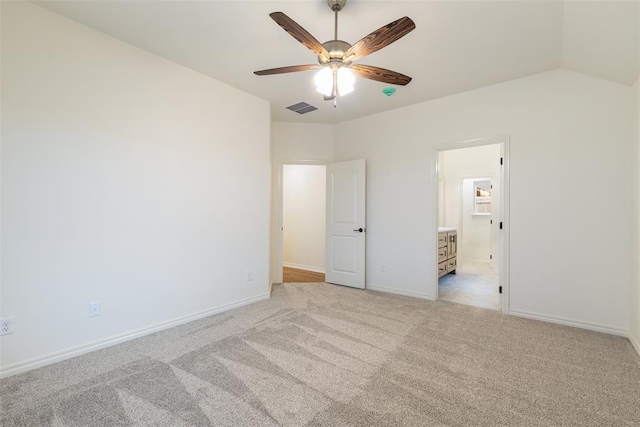 unfurnished bedroom featuring ceiling fan, light colored carpet, connected bathroom, and vaulted ceiling