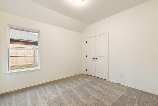 carpeted empty room featuring vaulted ceiling