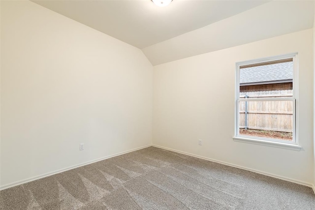 carpeted empty room featuring vaulted ceiling