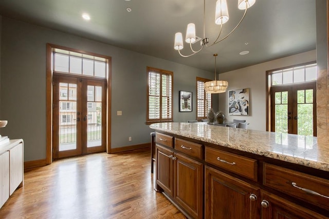 kitchen featuring french doors, a healthy amount of sunlight, light wood-type flooring, and a notable chandelier