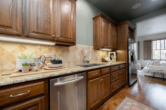 kitchen with backsplash, sink, dark hardwood / wood-style floors, appliances with stainless steel finishes, and light stone counters