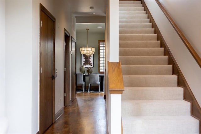 staircase with an inviting chandelier and hardwood / wood-style flooring