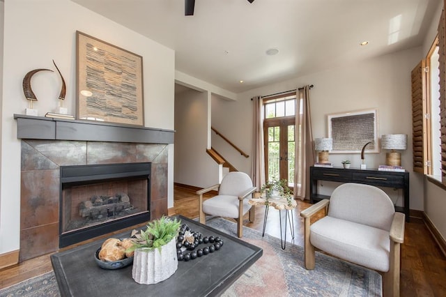 living room with a tile fireplace and dark hardwood / wood-style flooring