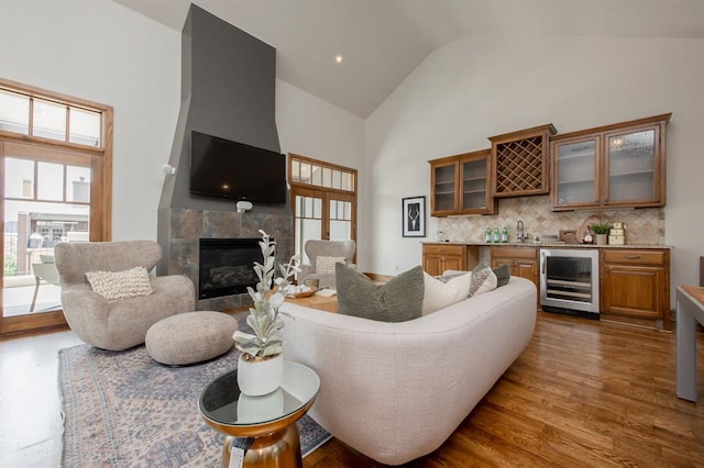 living room with dark wood-type flooring, beverage cooler, wet bar, high vaulted ceiling, and a fireplace