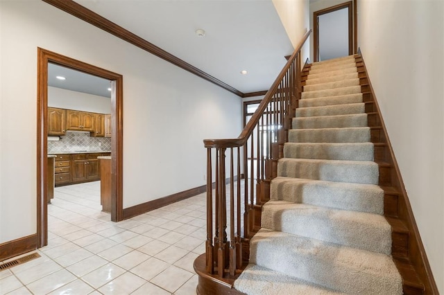 staircase with tile patterned flooring and ornamental molding