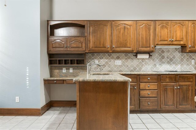 kitchen with decorative backsplash, light stone counters, black electric cooktop, a kitchen island, and light tile patterned flooring