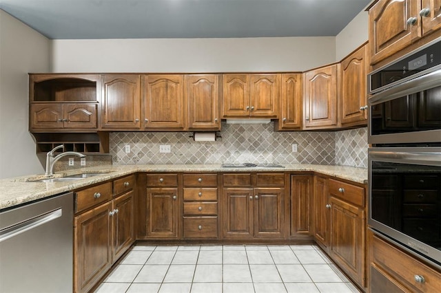 kitchen with backsplash, light stone countertops, sink, and stainless steel appliances