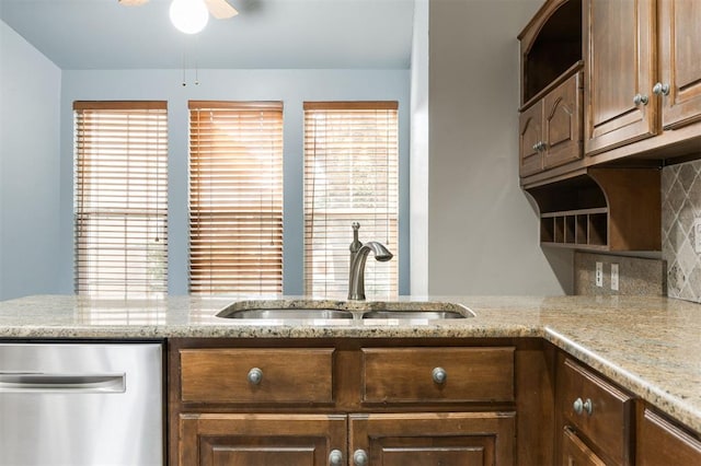 kitchen with sink, stainless steel dishwasher, decorative backsplash, ceiling fan, and light stone countertops