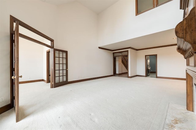 unfurnished living room featuring light colored carpet, high vaulted ceiling, and ornamental molding