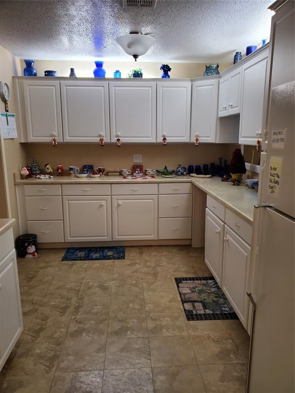 kitchen featuring white fridge and white cabinetry