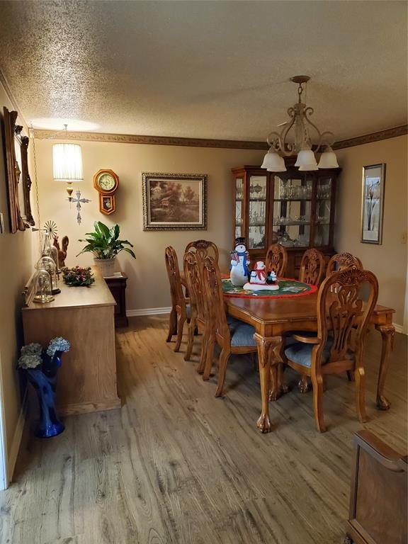 dining area featuring hardwood / wood-style floors, a notable chandelier, crown molding, and a textured ceiling