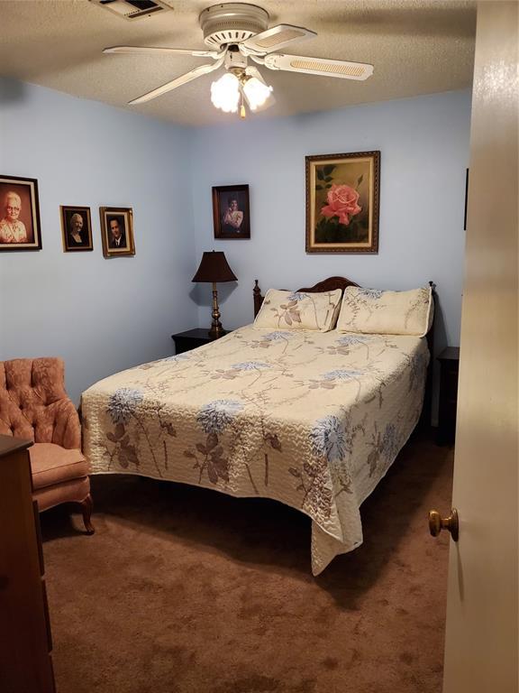 bedroom featuring dark colored carpet, ceiling fan, and a textured ceiling