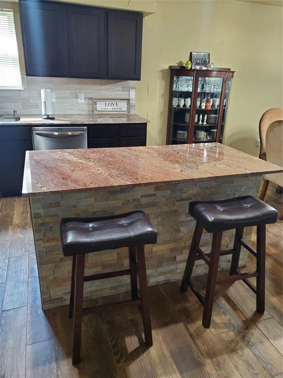 bar featuring backsplash, dark hardwood / wood-style flooring, and stainless steel dishwasher