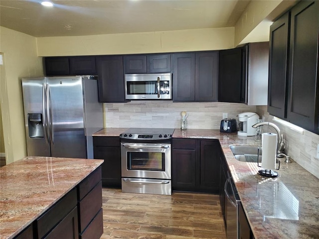 kitchen featuring light stone counters, sink, stainless steel appliances, and wood-type flooring