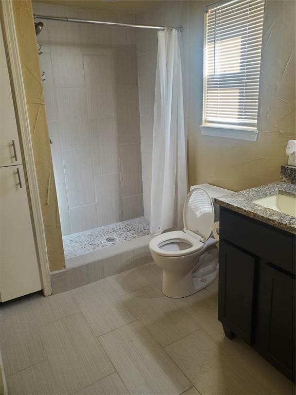 bathroom featuring tile patterned floors, vanity, toilet, and walk in shower