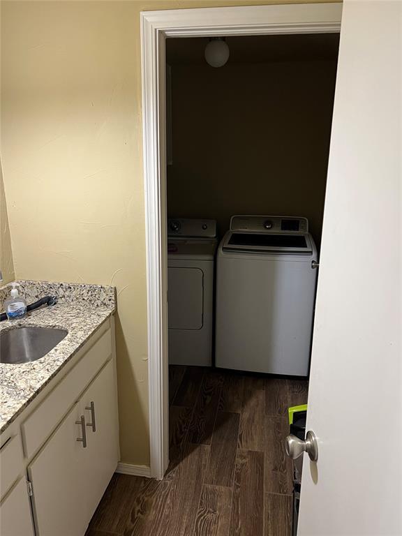 laundry area with separate washer and dryer, dark hardwood / wood-style floors, and sink