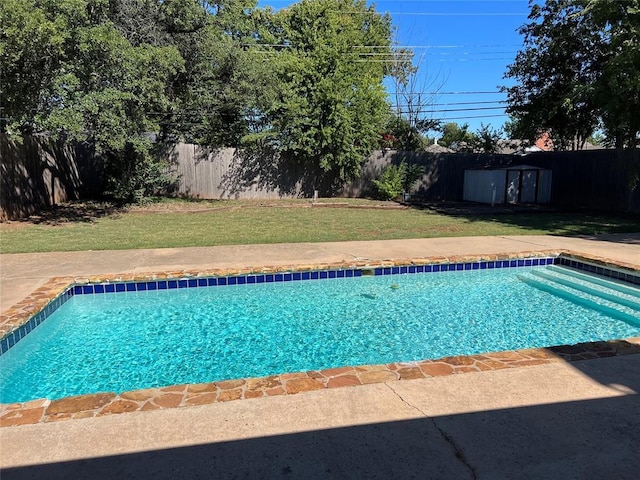 view of swimming pool with a yard and a storage unit