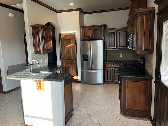 kitchen featuring dark stone counters, decorative backsplash, ornamental molding, appliances with stainless steel finishes, and kitchen peninsula