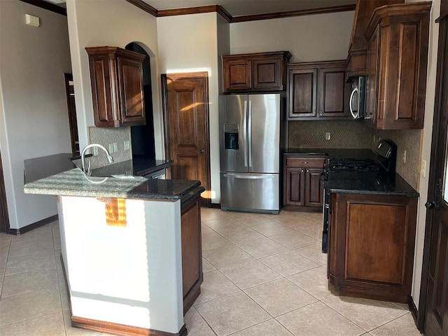 kitchen featuring decorative backsplash, ornamental molding, stainless steel appliances, light tile patterned floors, and dark stone countertops