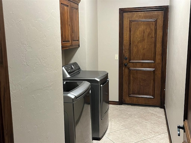 washroom featuring separate washer and dryer, light tile patterned floors, and cabinets