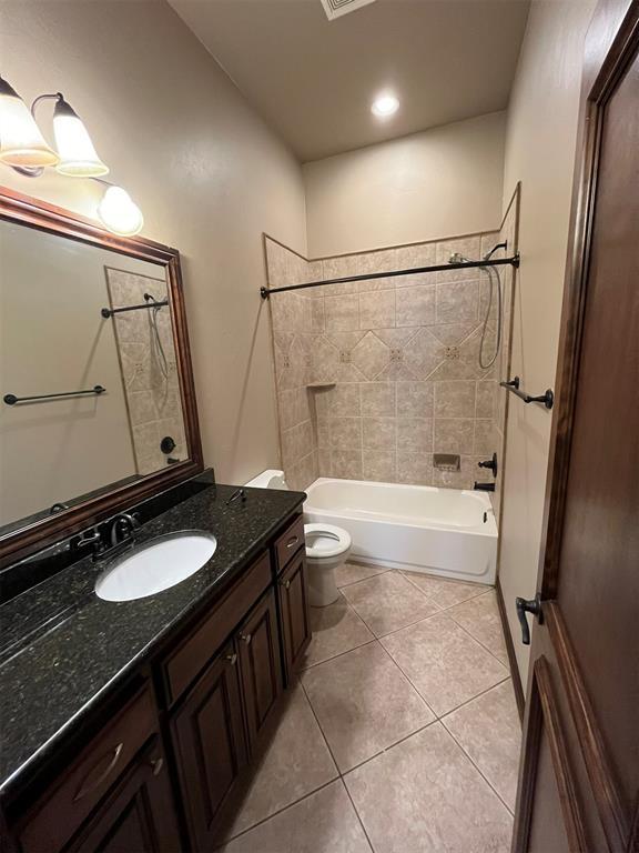 full bathroom with tile patterned flooring, vanity, tiled shower / bath combo, and toilet