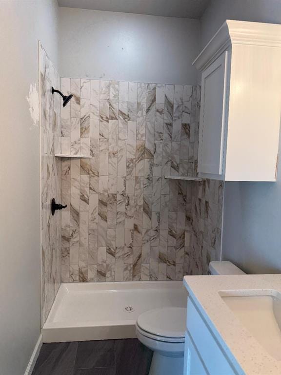 bathroom with vanity, toilet, baseboards, and a stall shower