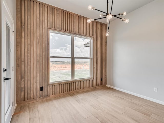 spare room featuring light wood-type flooring and an inviting chandelier