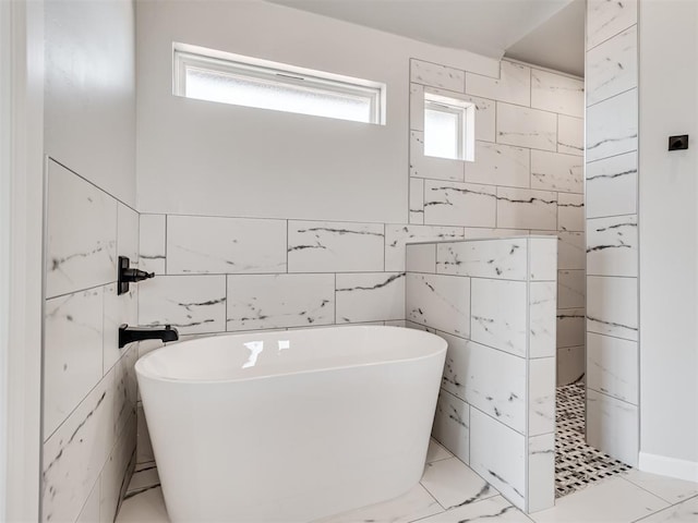 bathroom with a bathtub, a healthy amount of sunlight, and tile walls