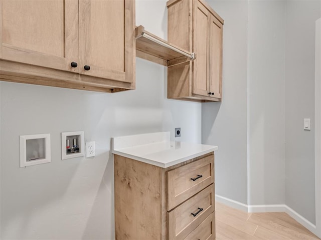 washroom featuring hookup for a washing machine, cabinets, light wood-type flooring, and hookup for an electric dryer