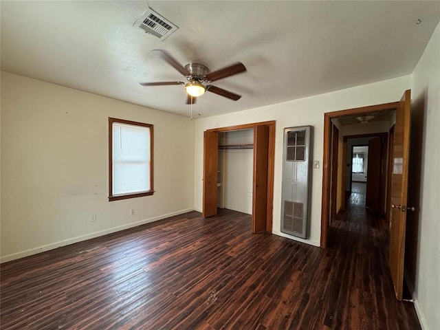 unfurnished bedroom featuring ceiling fan, a closet, and dark wood-type flooring