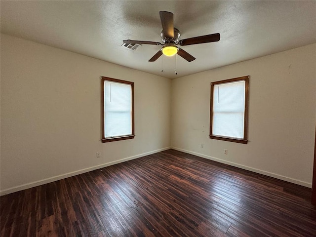 spare room featuring ceiling fan, dark wood-type flooring, and a wealth of natural light