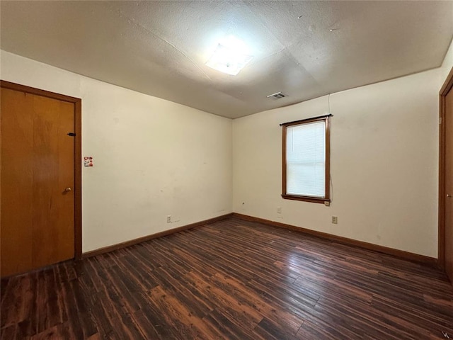 spare room with a textured ceiling and dark wood-type flooring