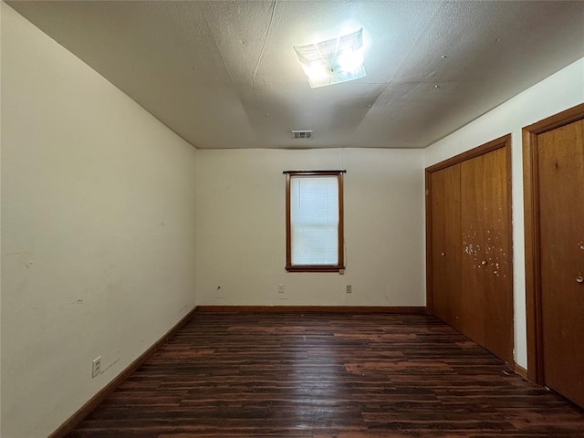 unfurnished bedroom featuring dark hardwood / wood-style flooring and multiple closets