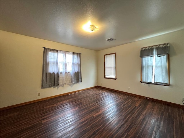 spare room featuring a textured ceiling and dark hardwood / wood-style floors