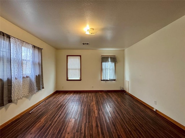 spare room with a textured ceiling and dark hardwood / wood-style flooring